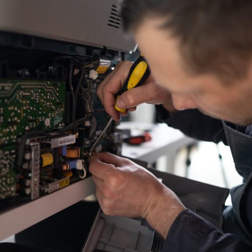 printer repair technician. A male handyman inspects a printer be